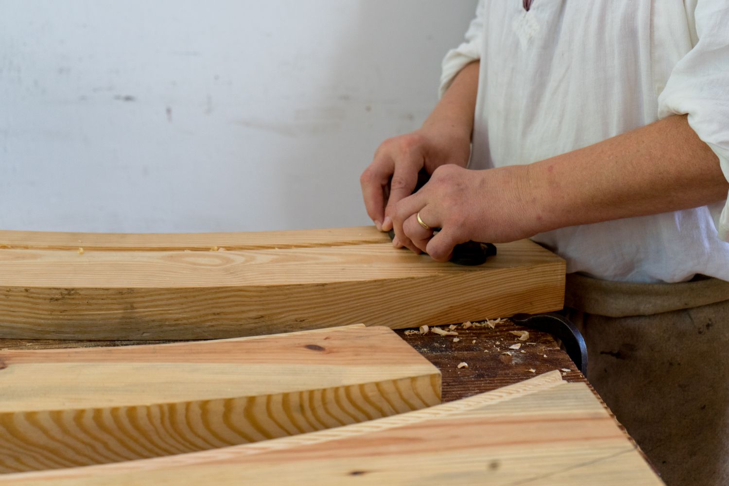 Mains d'artisan qui lissent une planche de bois