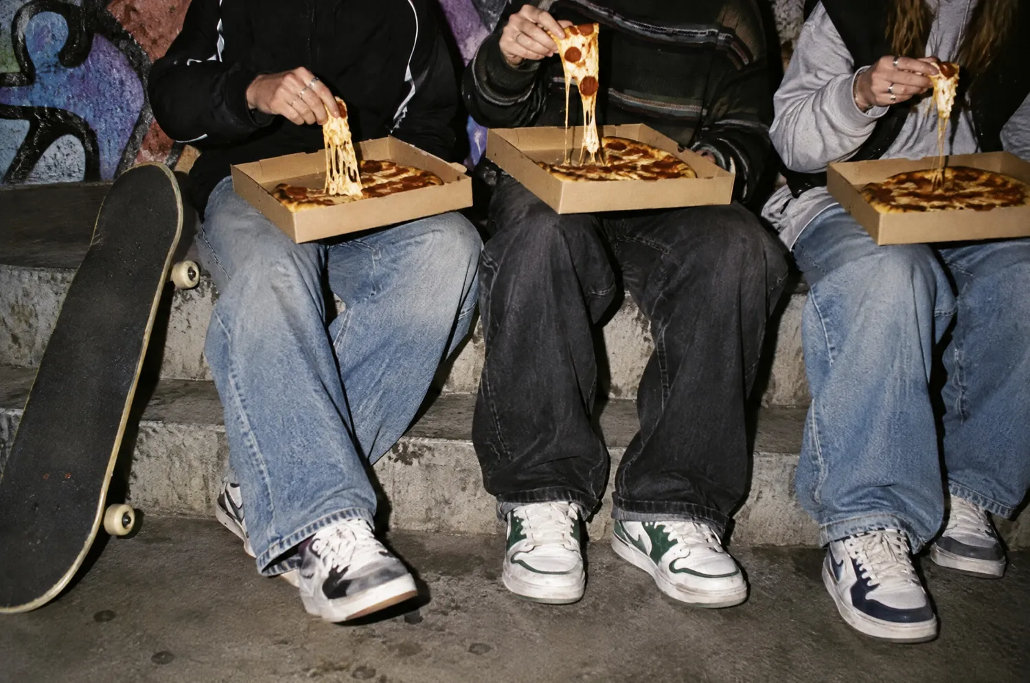 Trois amis partagent des pizzas assis sur des marches